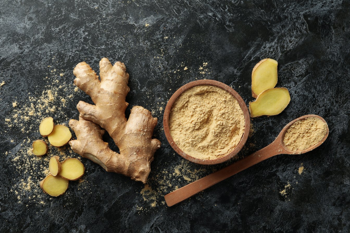 Ginger and Bowl with Ginger Powder on Black Smoky Background